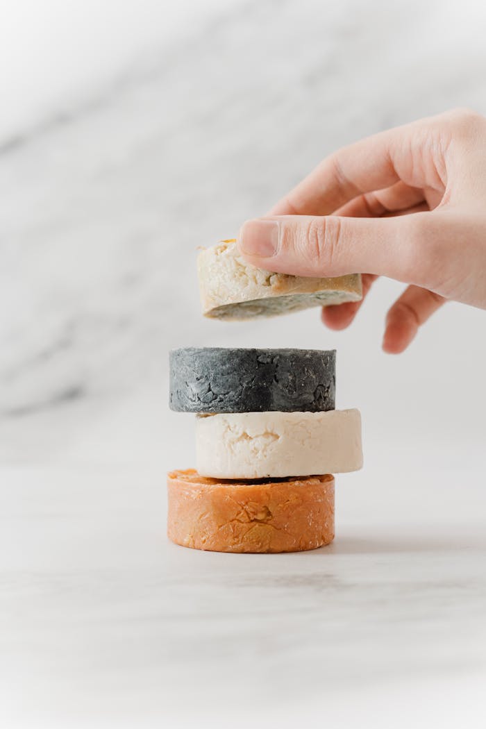 A hand placing eco-friendly soap bars in a stack, promoting zero waste and sustainable living.