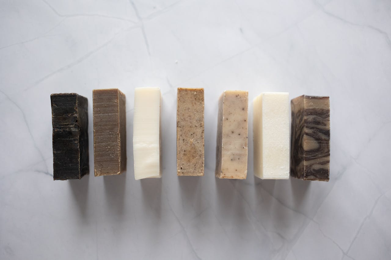 Collection of handcrafted natural soaps on a marble surface, showcasing earthy tones and textures.