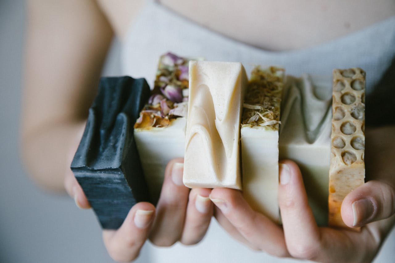 A variety of handcrafted organic soaps held in hands, showcasing natural ingredients and textures.