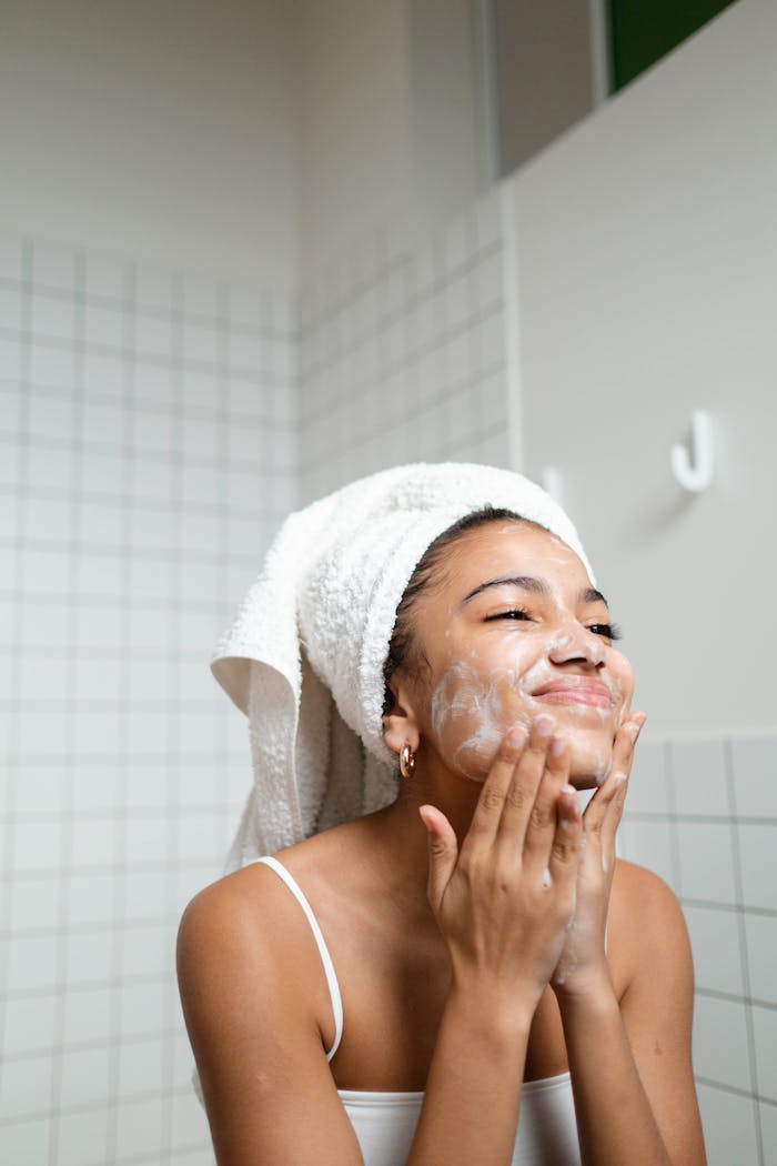 A young woman enjoying her skincare routine with a towel wrapped, indoors.