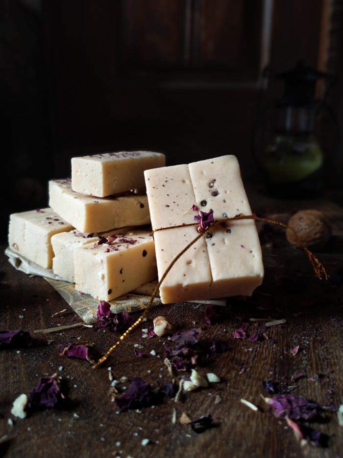 Handmade soap bars with dried rose petals on a rustic wooden table, perfect for organic beauty.